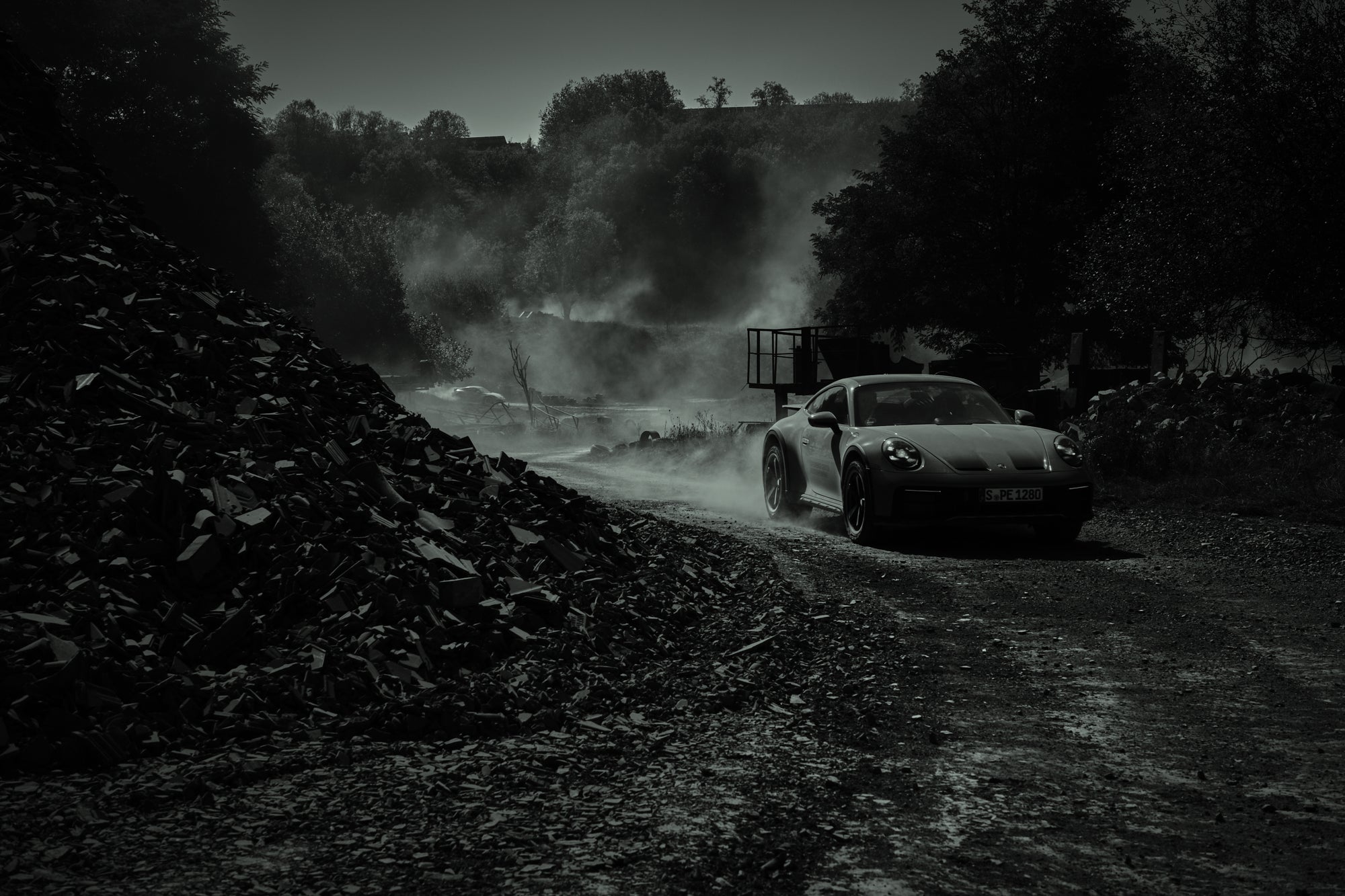 Fine art photography by Frank Kayser – Porsche 911 Dakar driving past a mountain of black rubble in a dusty quarry setting.