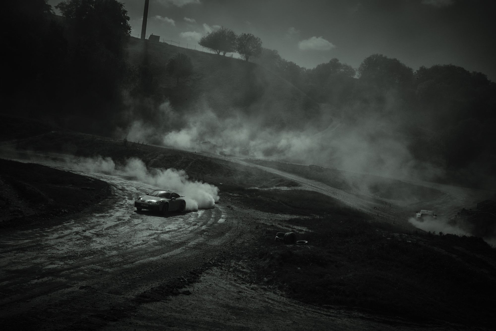 Fine art photography by Frank Kayser – Porsche 911 Dakar drifting through winding dirt roads, wrapped in dramatic clouds of dust.