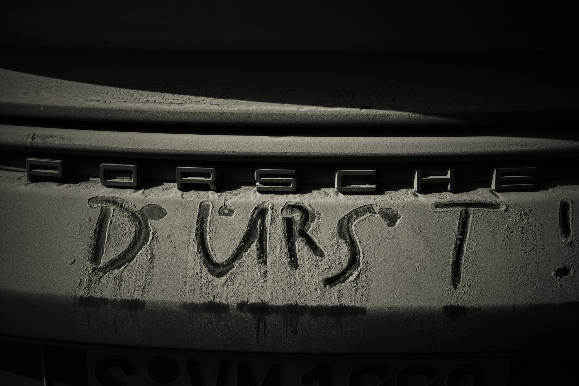 Fine art photography by Frank Kayser – the word “DURST” written in dust on the rear of a Porsche, raw and playful detail.