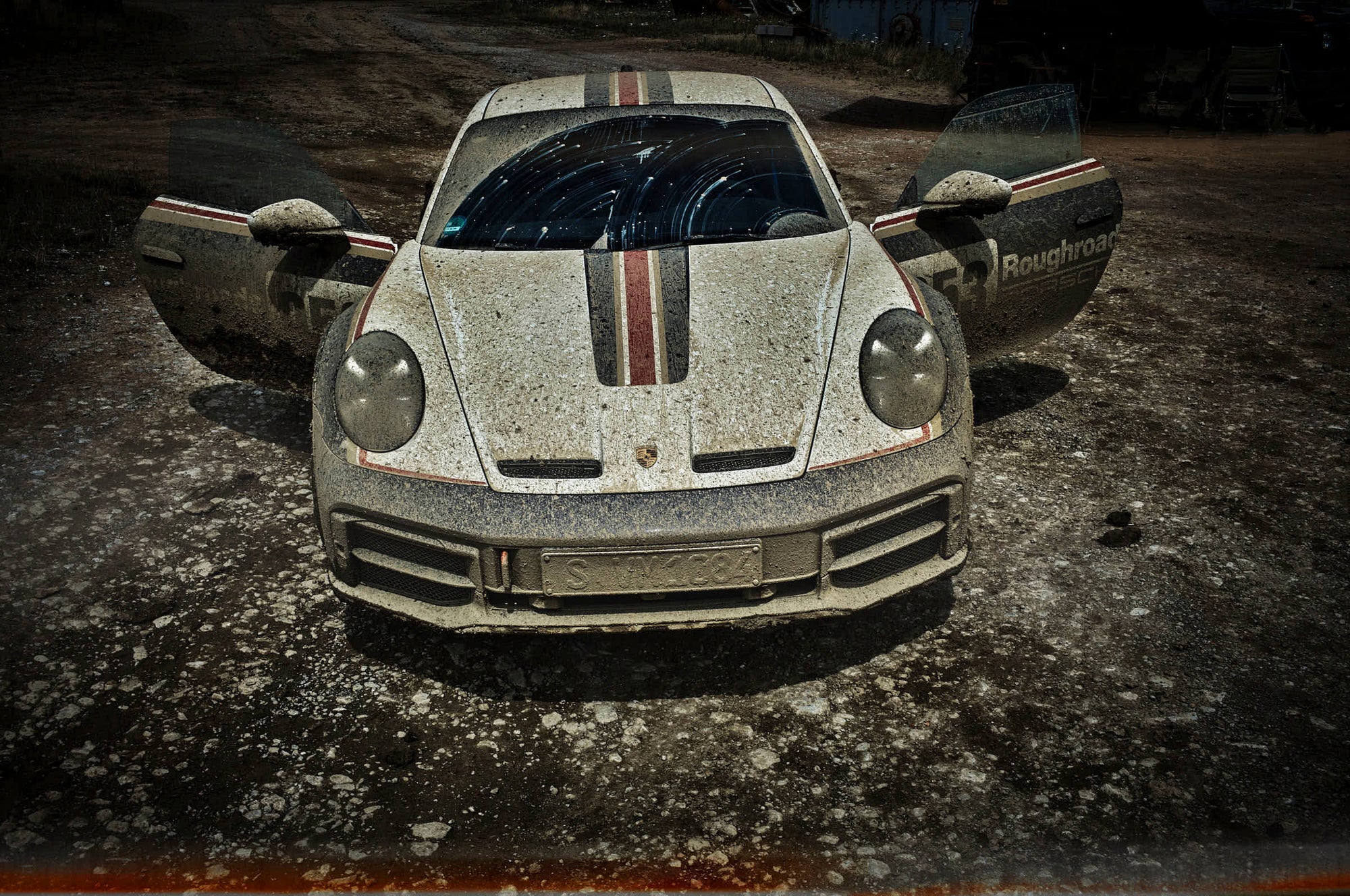 Frontimage of a muddy Porsche 911 dakar with open doors