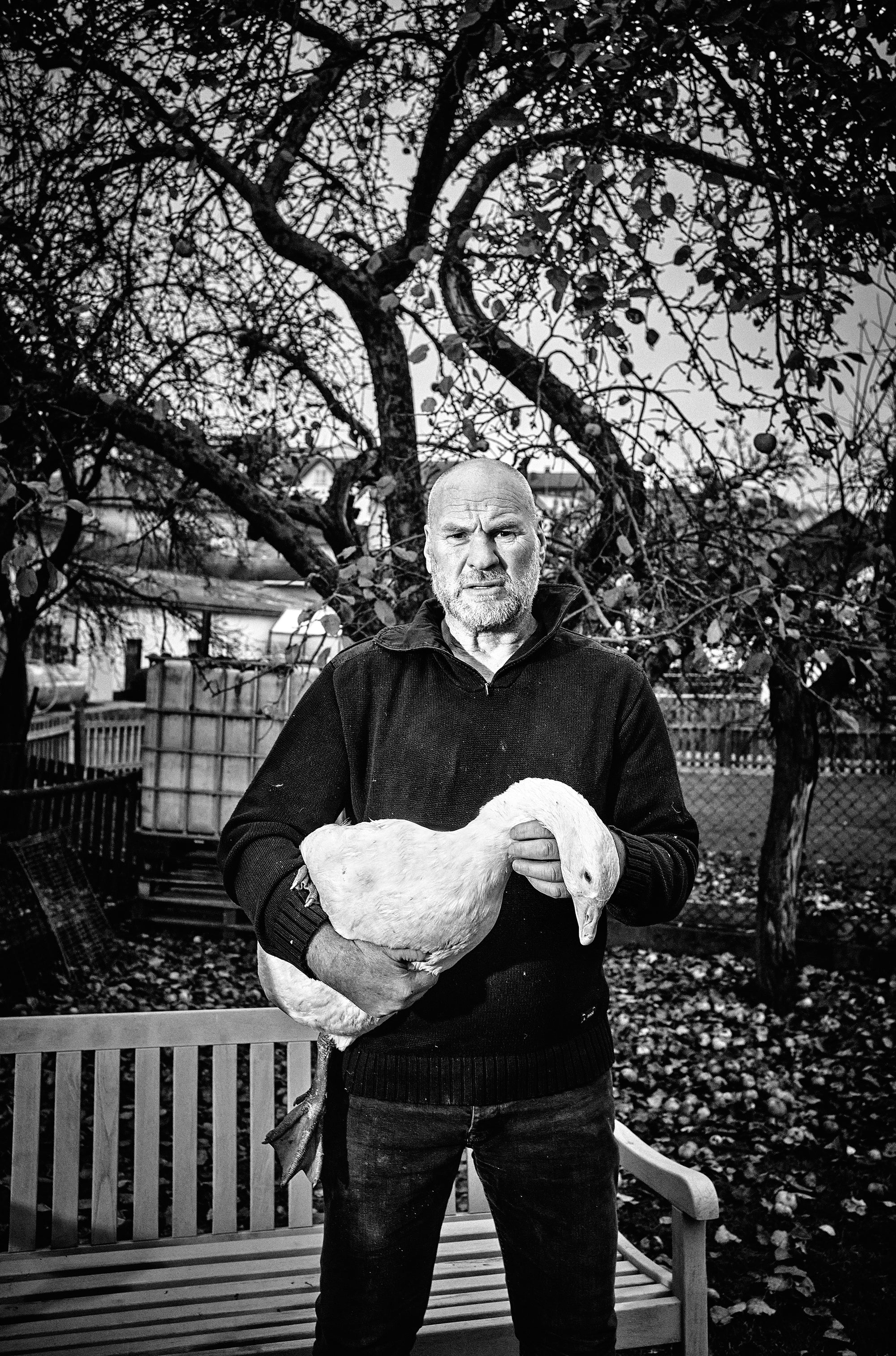 Fine art photography by Frank Kayser – portrait of a farmer holding a goose under an apple tree, symbol of rural life in the Rhön.