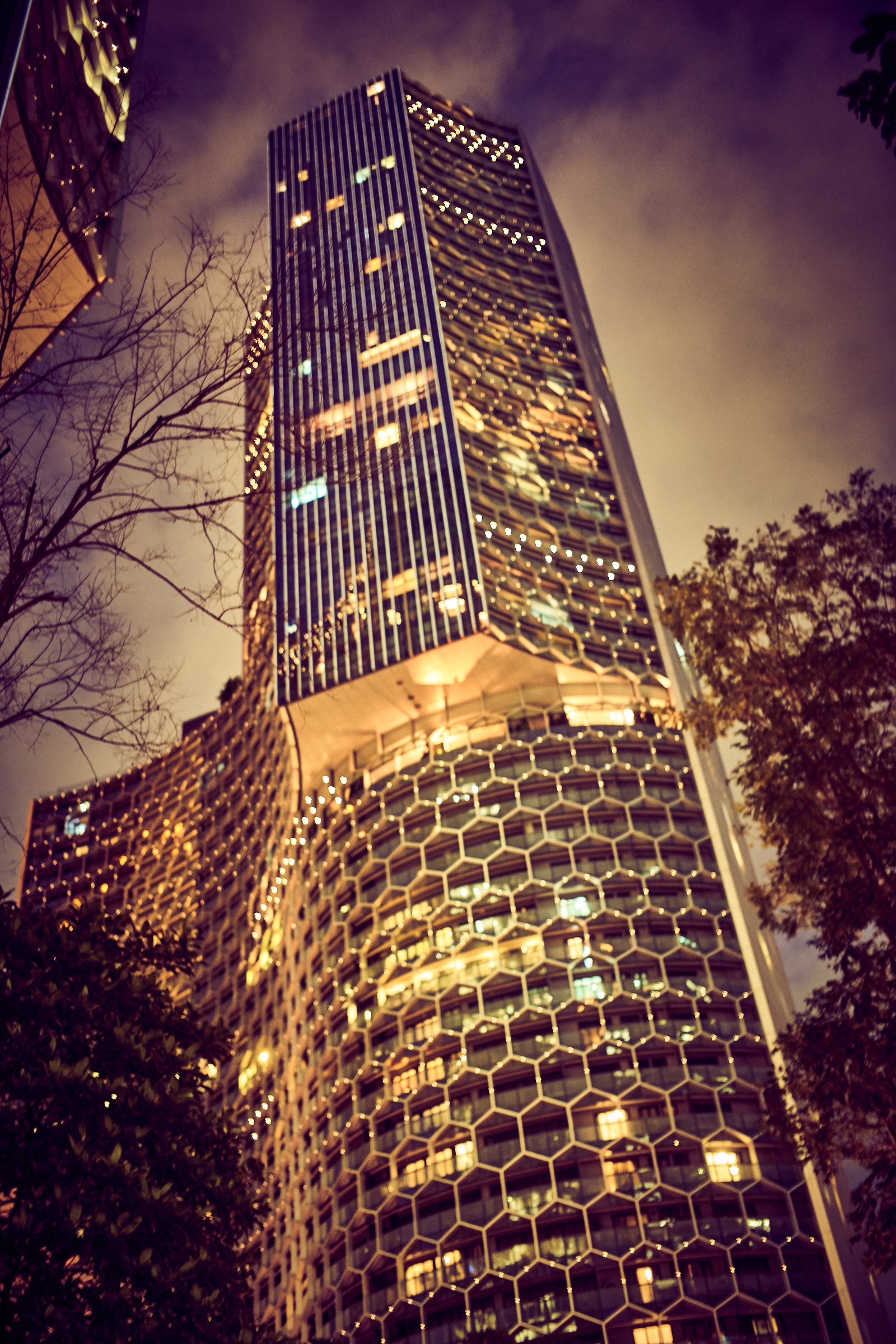 Fine art photography print by Frank Kayser – illuminated honeycomb-structured skyscraper in Singapore at night, dramatic cityscape architecture, limited edition wall art.