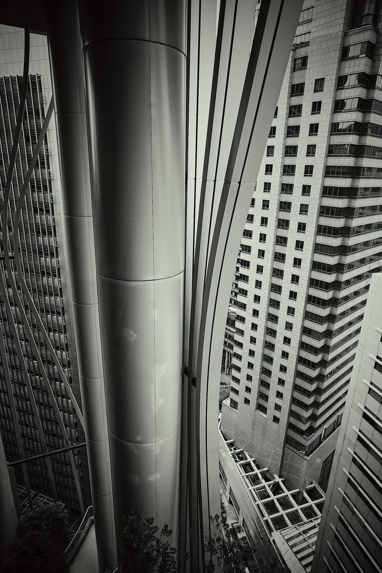 Monochrome view of sweeping silver structural columns and vertical fins between high-rise façades, Singapore.