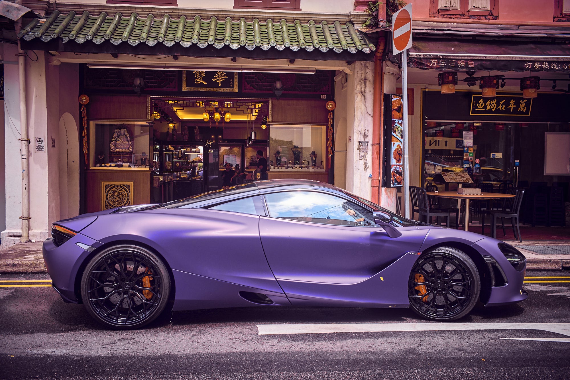 Fine art automotive photography by Frank Kayser – purple McLaren supercar parked in front of traditional Chinese shophouses in Singapore, fusion of modern speed and cultural heritage.