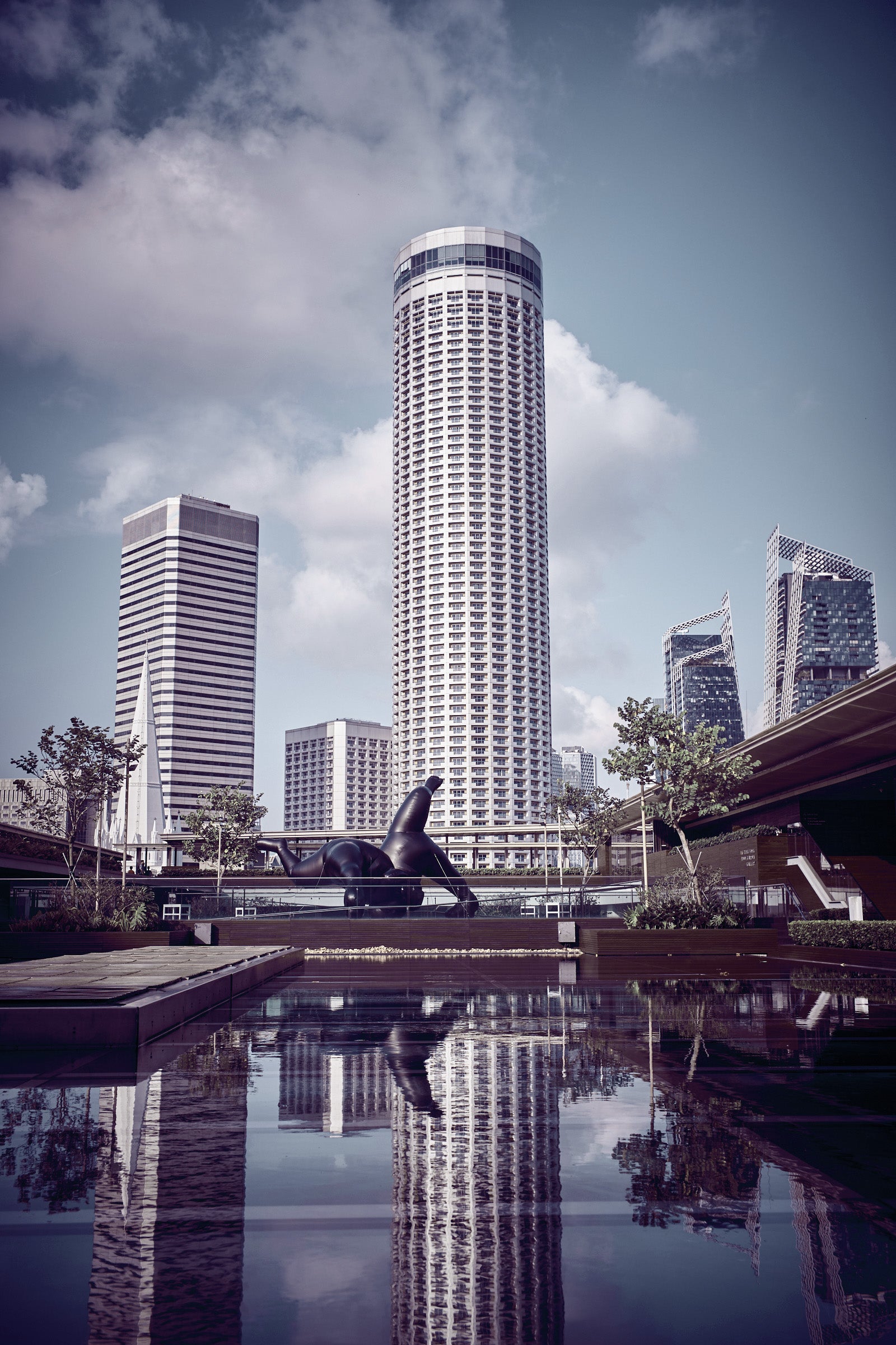 Cylindrical Singapore tower reflected in a still water basin, skyline and sculpture — fine art photograph by Frank Kayser.