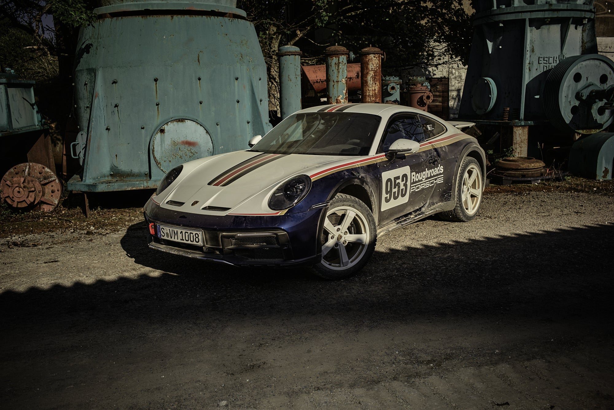 Fine art photography by Frank Kayser – Porsche 911 Dakar parked among monumental industrial machines, evoking cinematic urban drama.