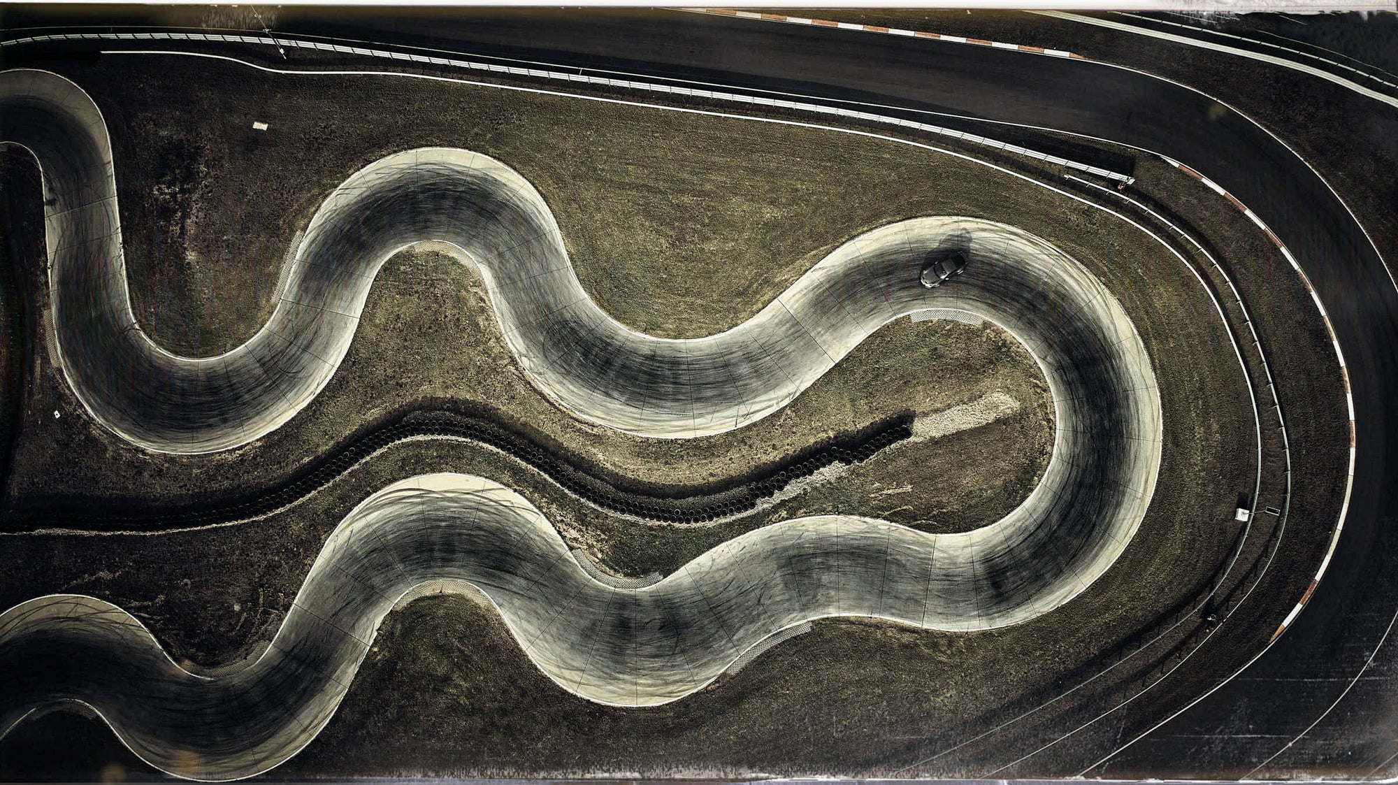 Fine art aerial photo by Frank Kayser – Porsche 911 Dakar sweeping through a winding S-curve.