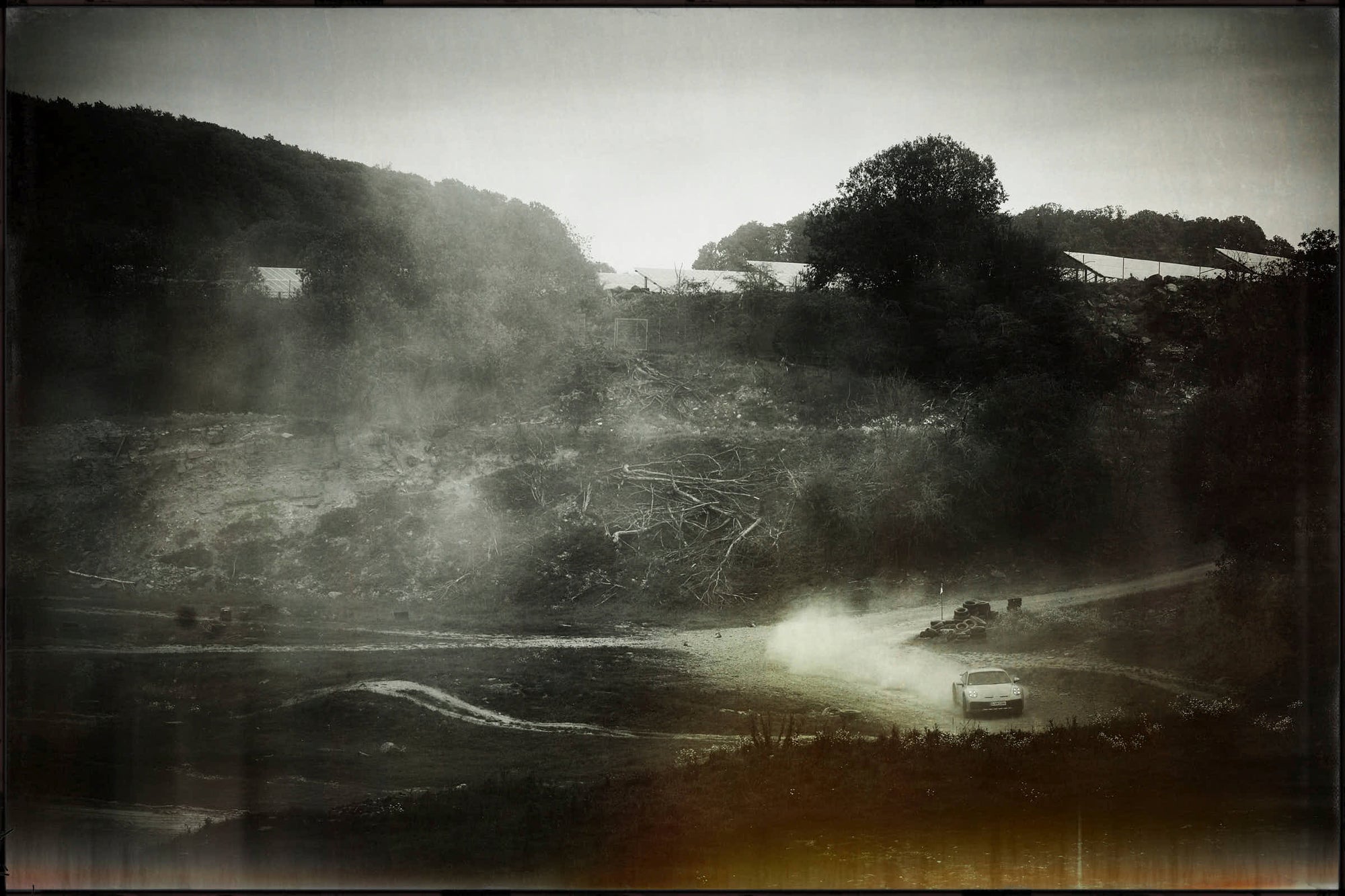 Fine art photo of Porsche 911 Dakar drifting in a wide valley, clouds of dust rising.