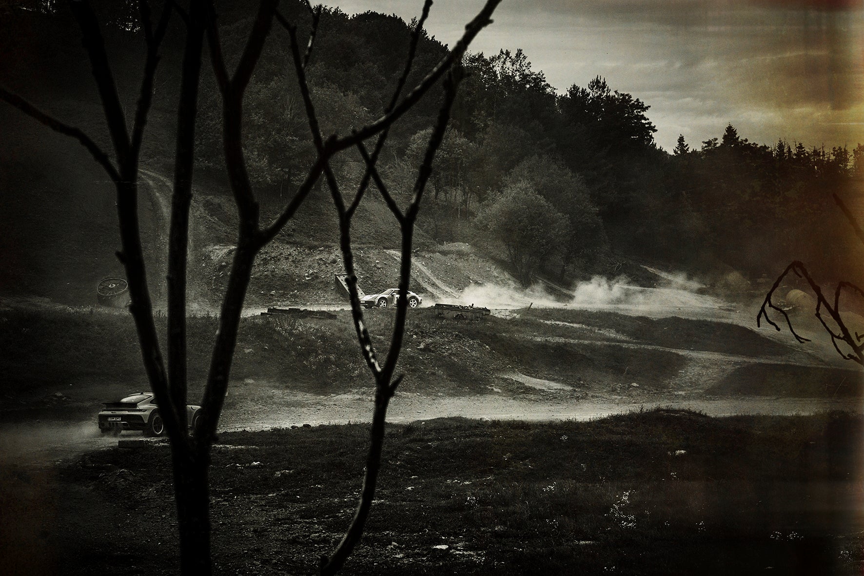 Fine art photo by Frank Kayser – Porsche Dakar drifting through dark morning light, trees in silhouette.